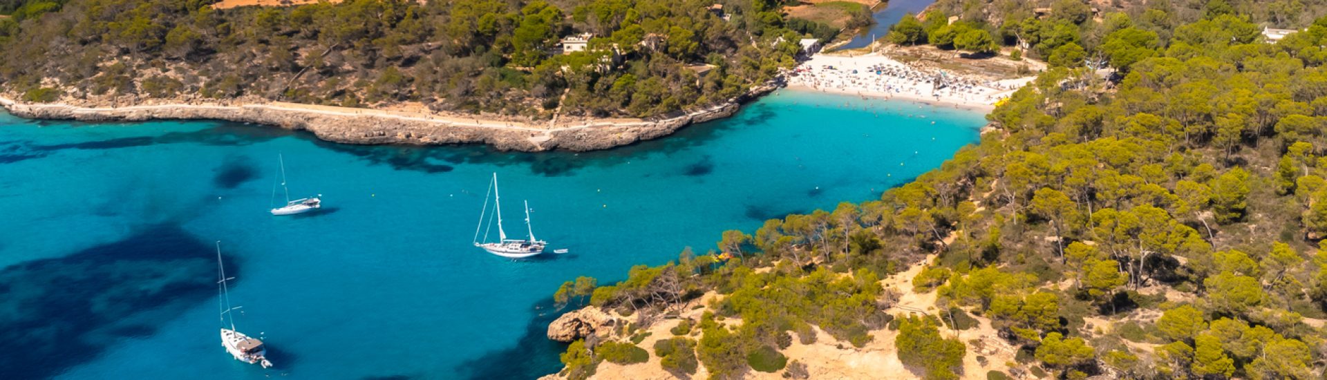 Aerial view capturing sailboats navigating the crystal clear turquoise waters of cala s'amarador and cala mondrago in mallorca